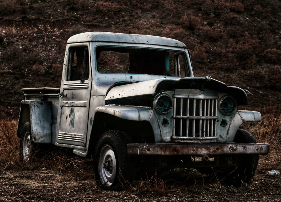 An old, abandoned pickup truck rusting in a dry field, evoking a sense of nostalgia and decay.