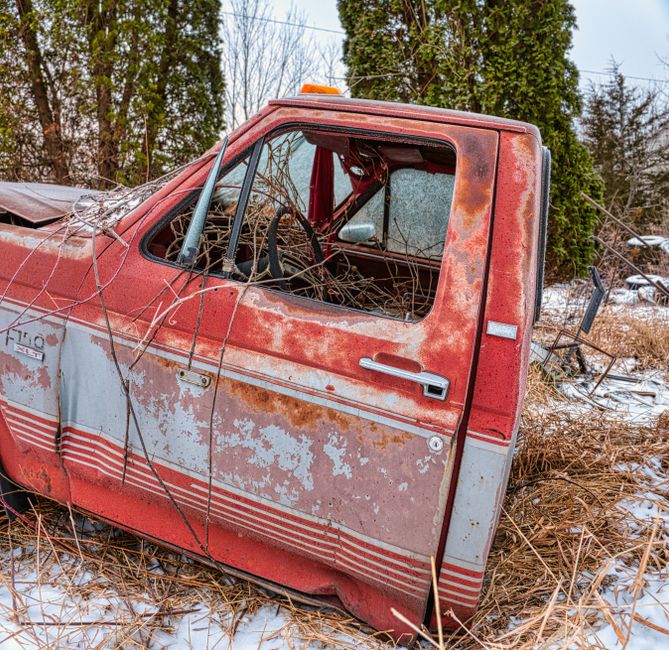 An old, rusty vintage truck abandoned in a snowy field.