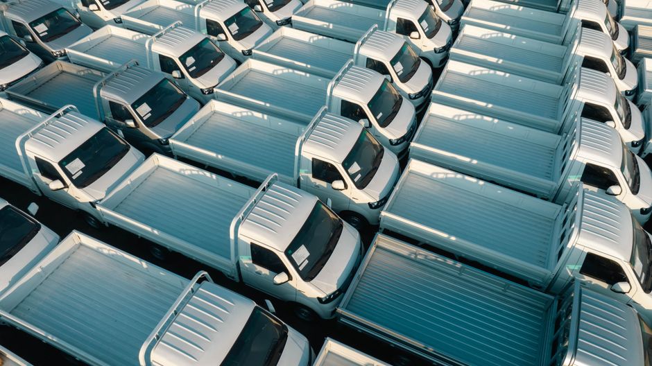 Aerial view of white pickup trucks parked in rows, emphasizing symmetry and industrial style.